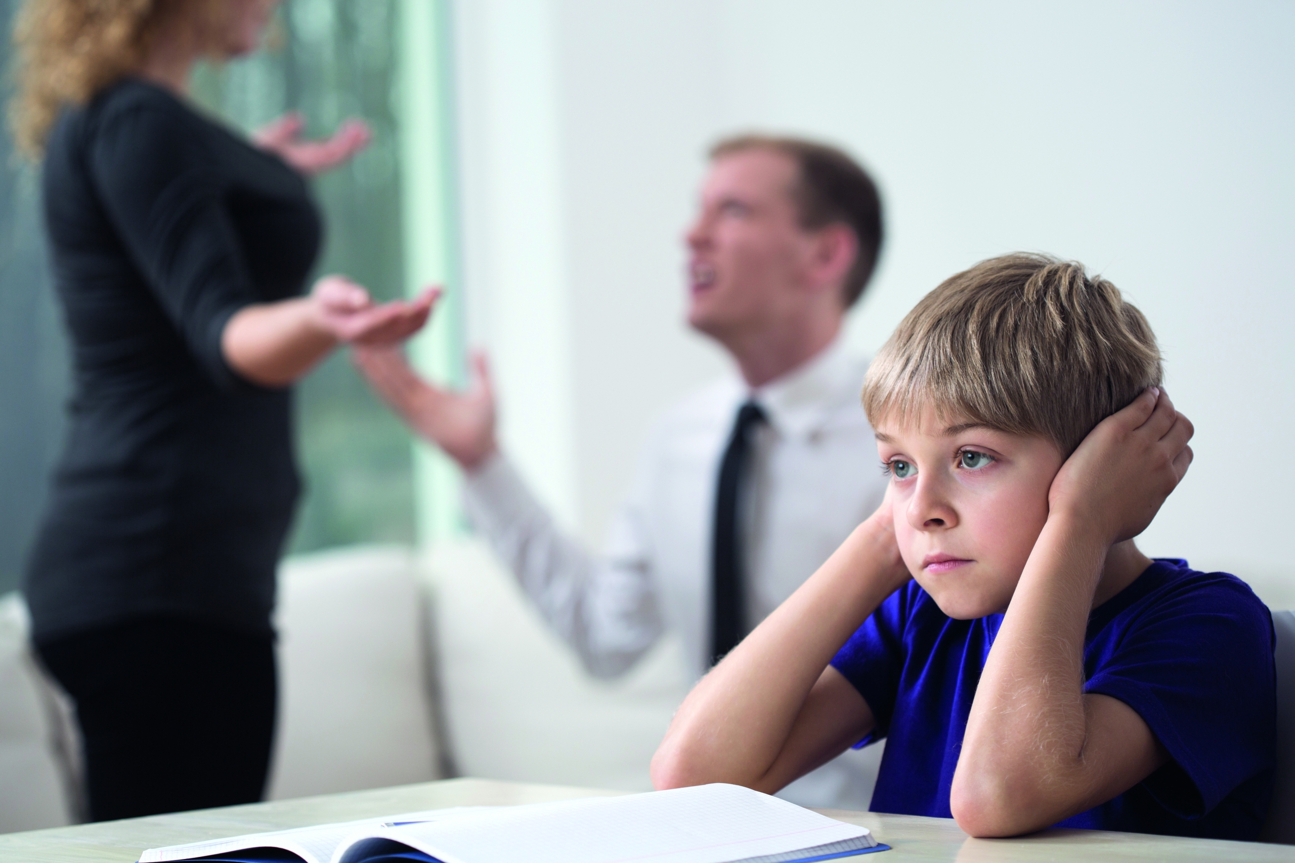 Boy covers his ears while his parents argue in background