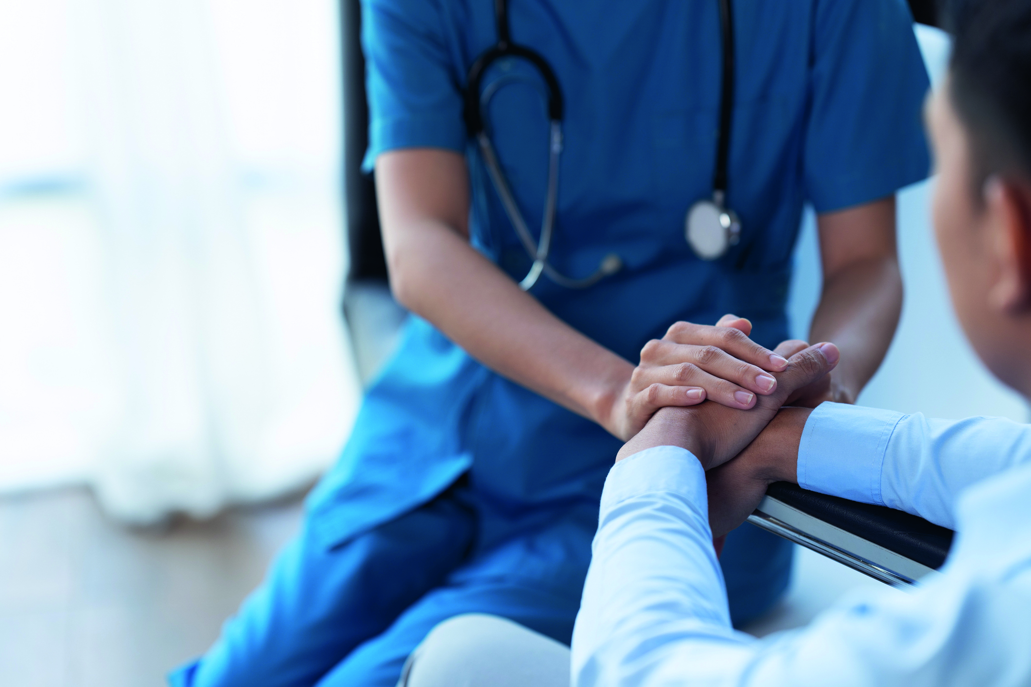 Doctor and patient sitting and talking at medical examination at hospital office, close-up. Therapist filling up medication history records. Medicine and healthcare concept.
