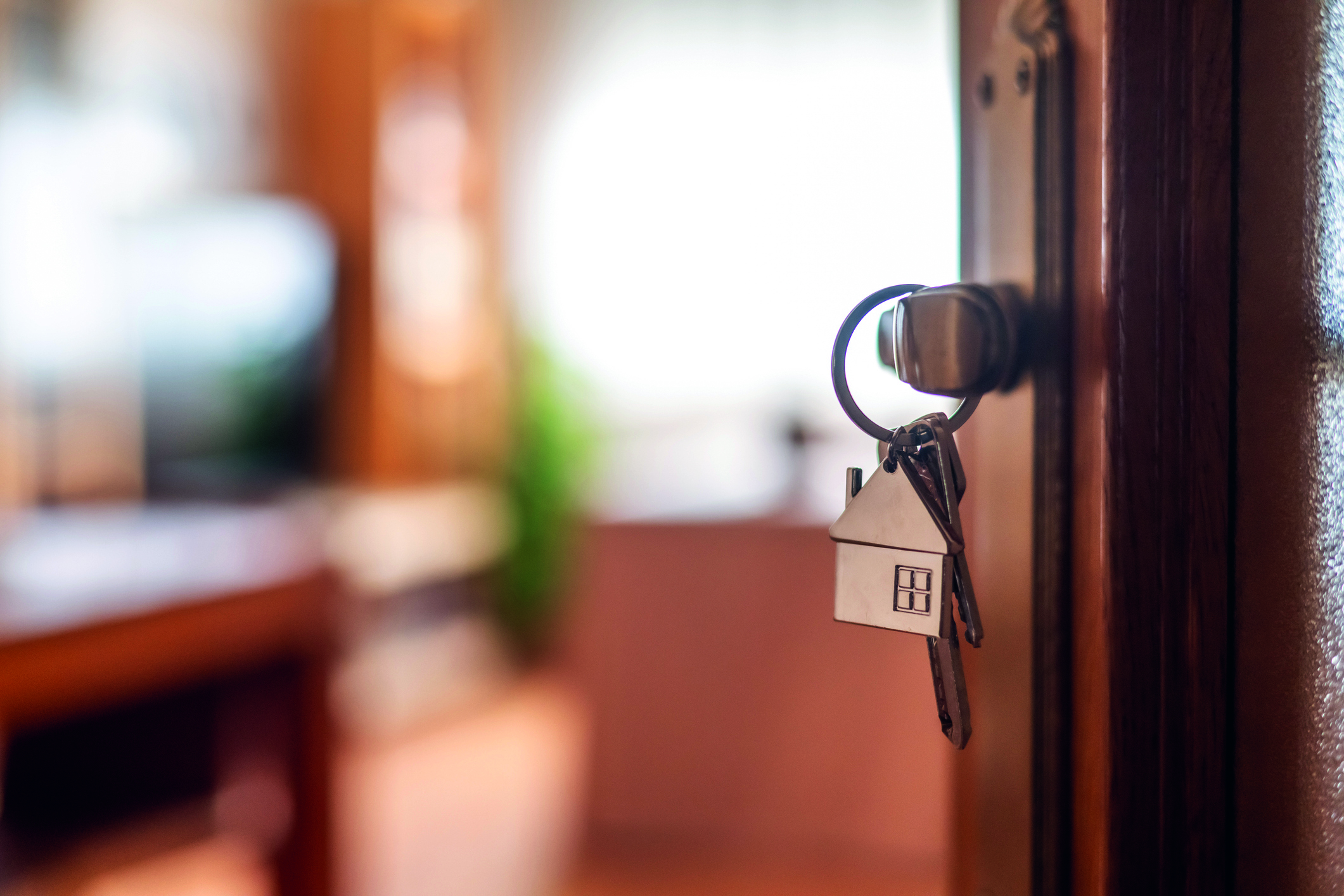 House-shaped keys are hanging from the door knob of a new home, representing the exciting moment of acquiring property and starting a fresh chapter